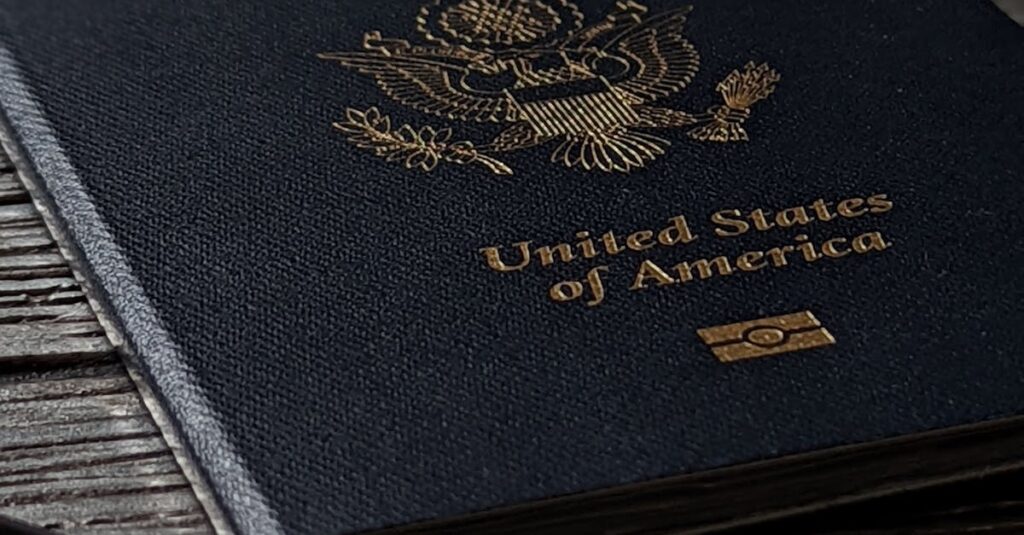 Close-up of a United States passport on a rustic wooden table with a smartphone nearby.