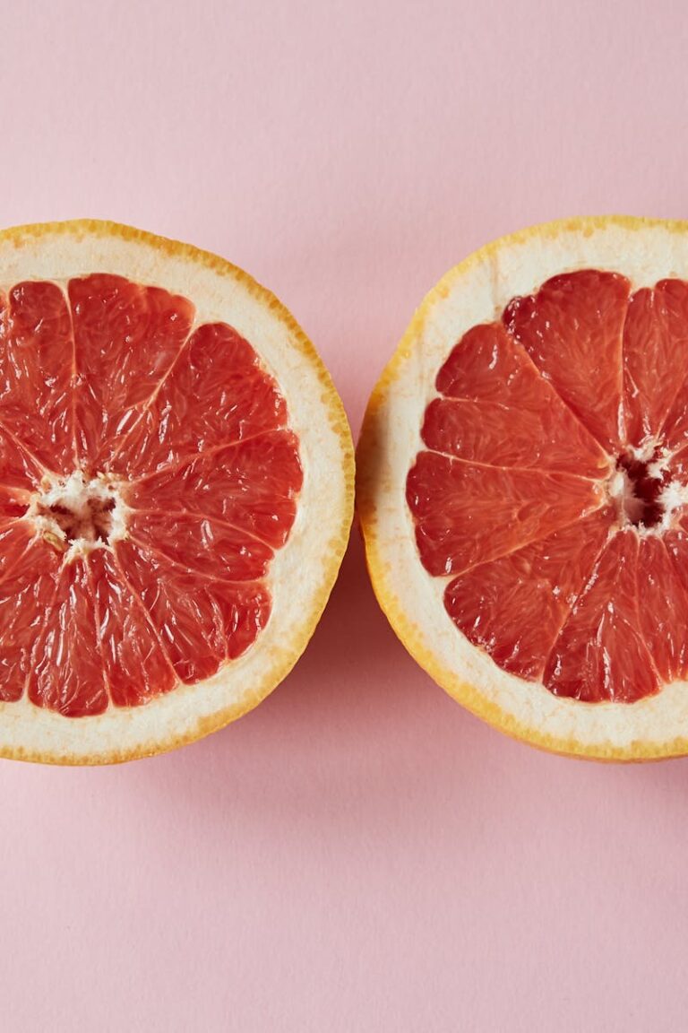 Top view of fresh sliced juicy grapefruit placed on pink background in studio