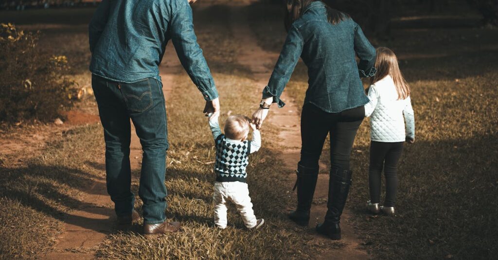 A family of four walks hand in hand on a path, enjoying a sunny day outdoors.